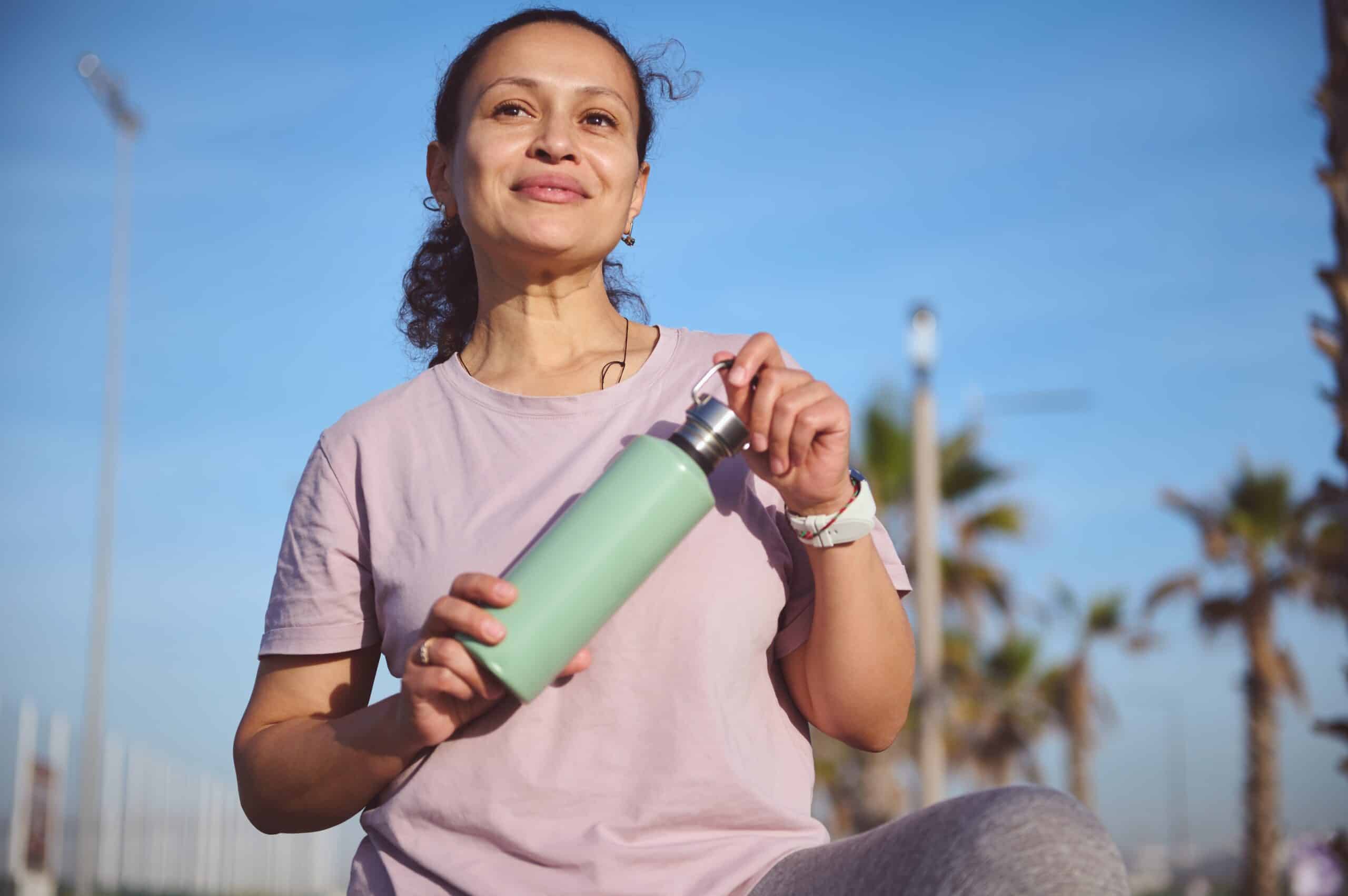 Lady holding a green water bottle whilst exercising