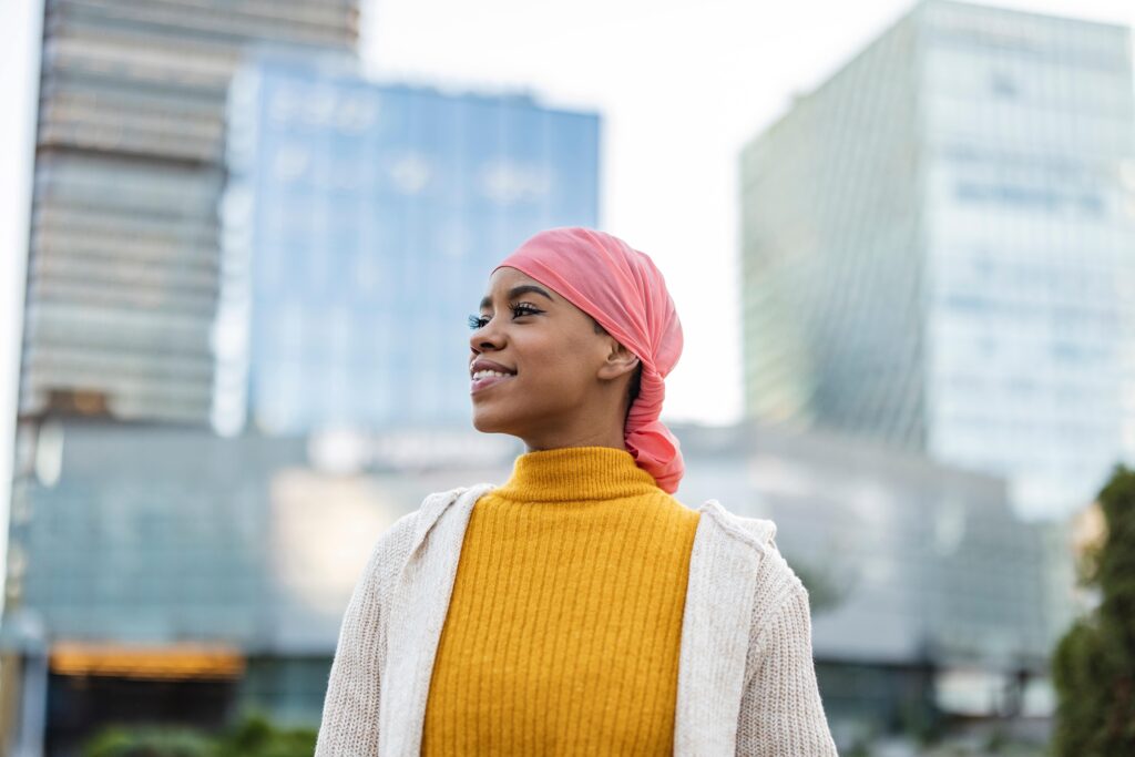 shutterstock_2265809097-min You woman stood in a city wearing a head covering